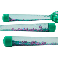 Three transparent tubes with green lids filled with colorful sand and water.